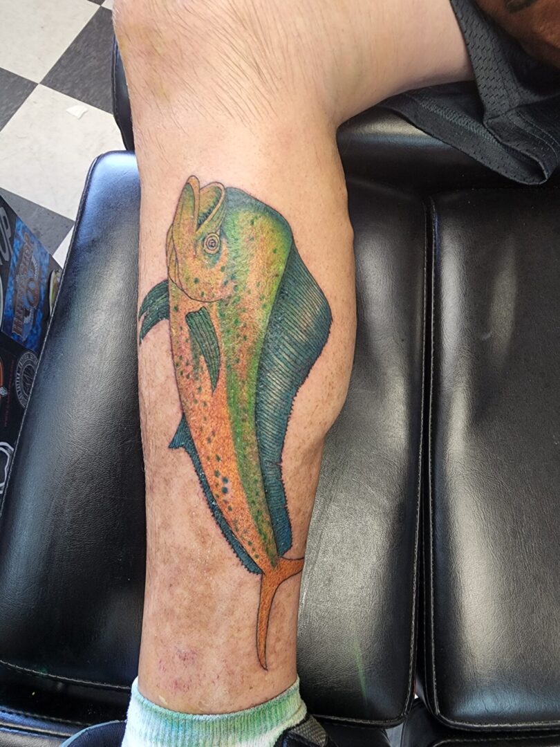 A green huge fish as a calf tattoo
