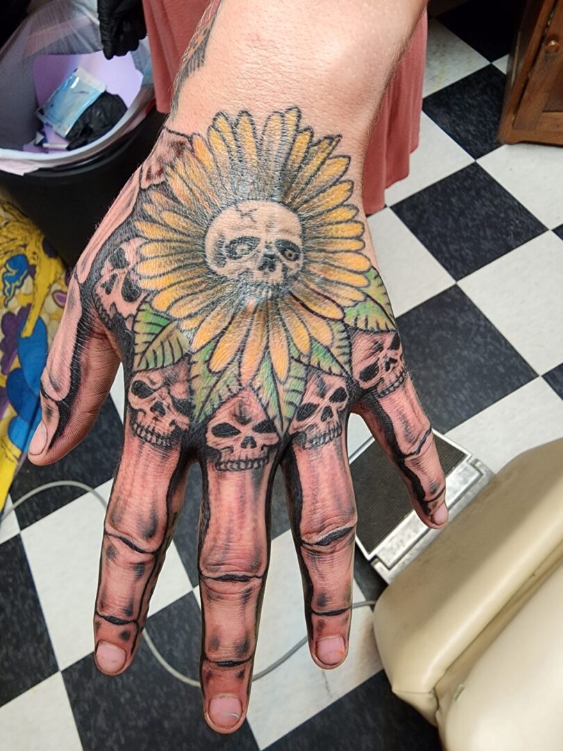 Skull with yellow flowers as a fist tattoo