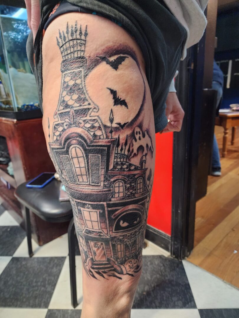 A haunted building as a thigh tattoo