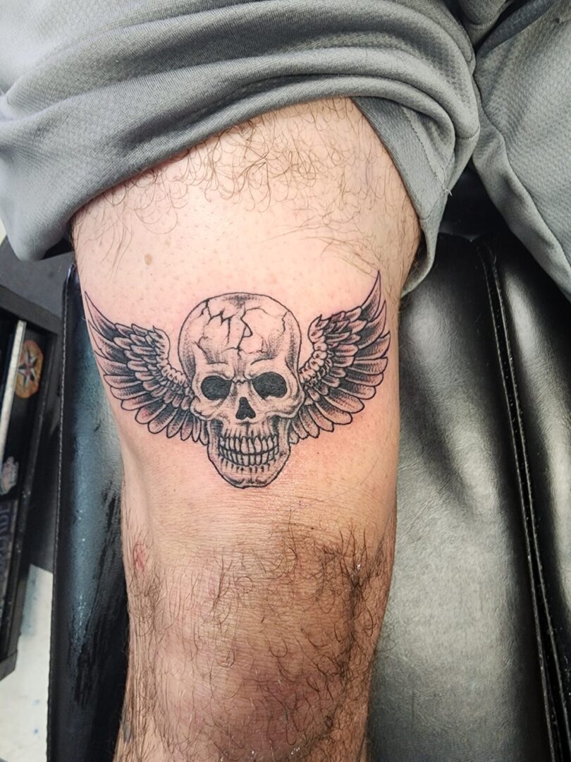 A skull with wings as a leg tattoo