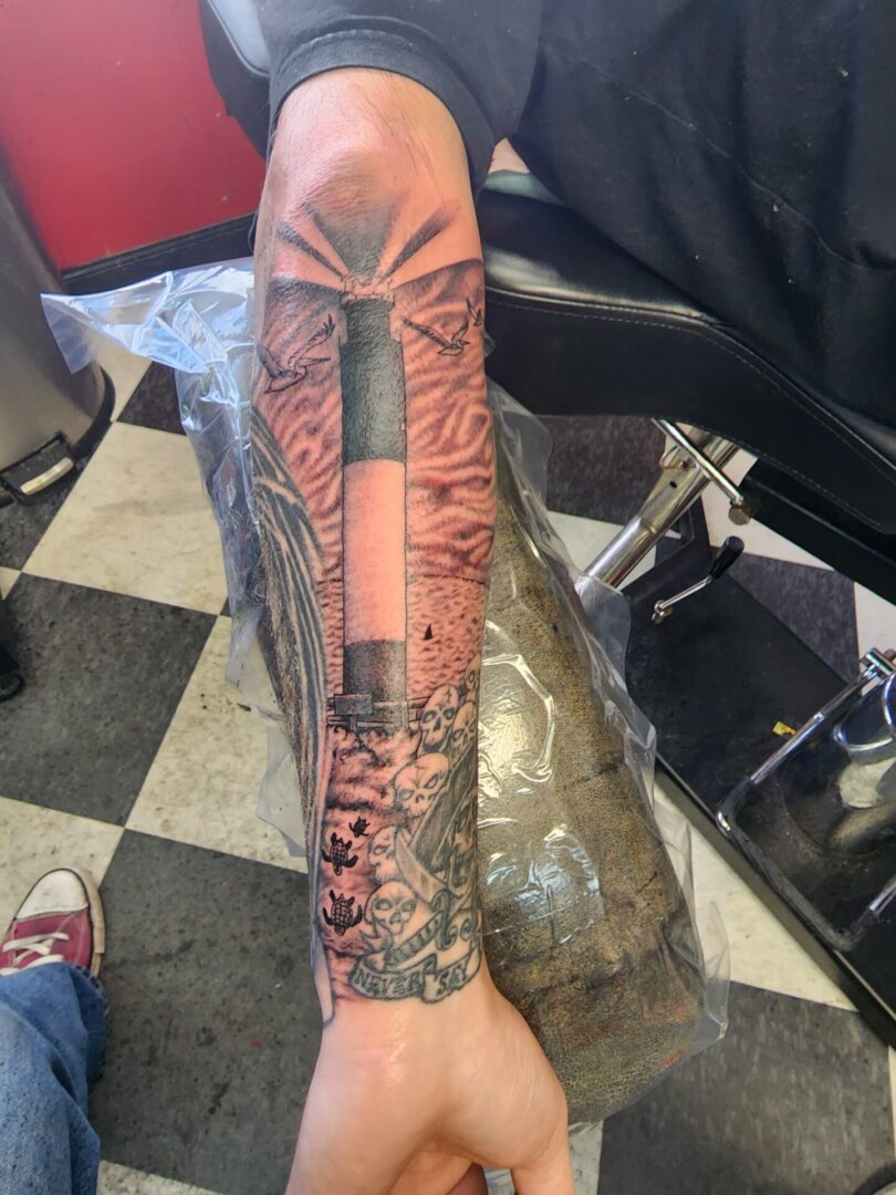 A lighthouse with birds as an arm tattoo